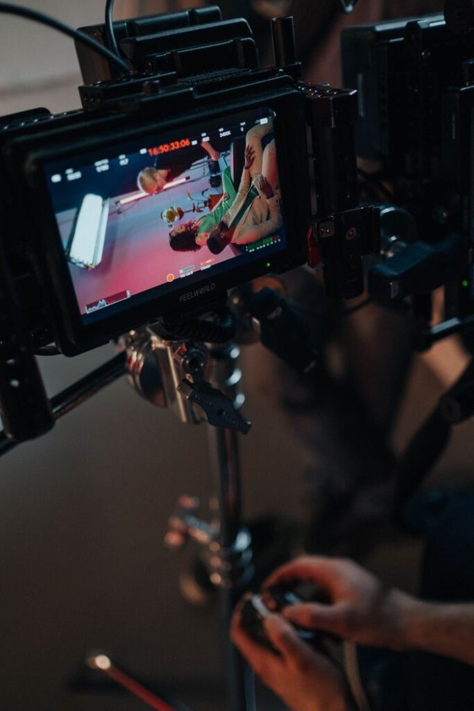 Close-up of a video camera setup with screen showing preview on set.