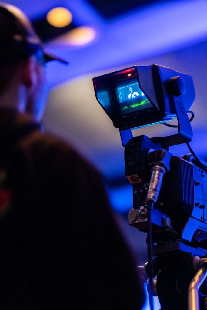 A professional filmmaker operating a high-end camera rig during a video shoot in a dimly lit environment.